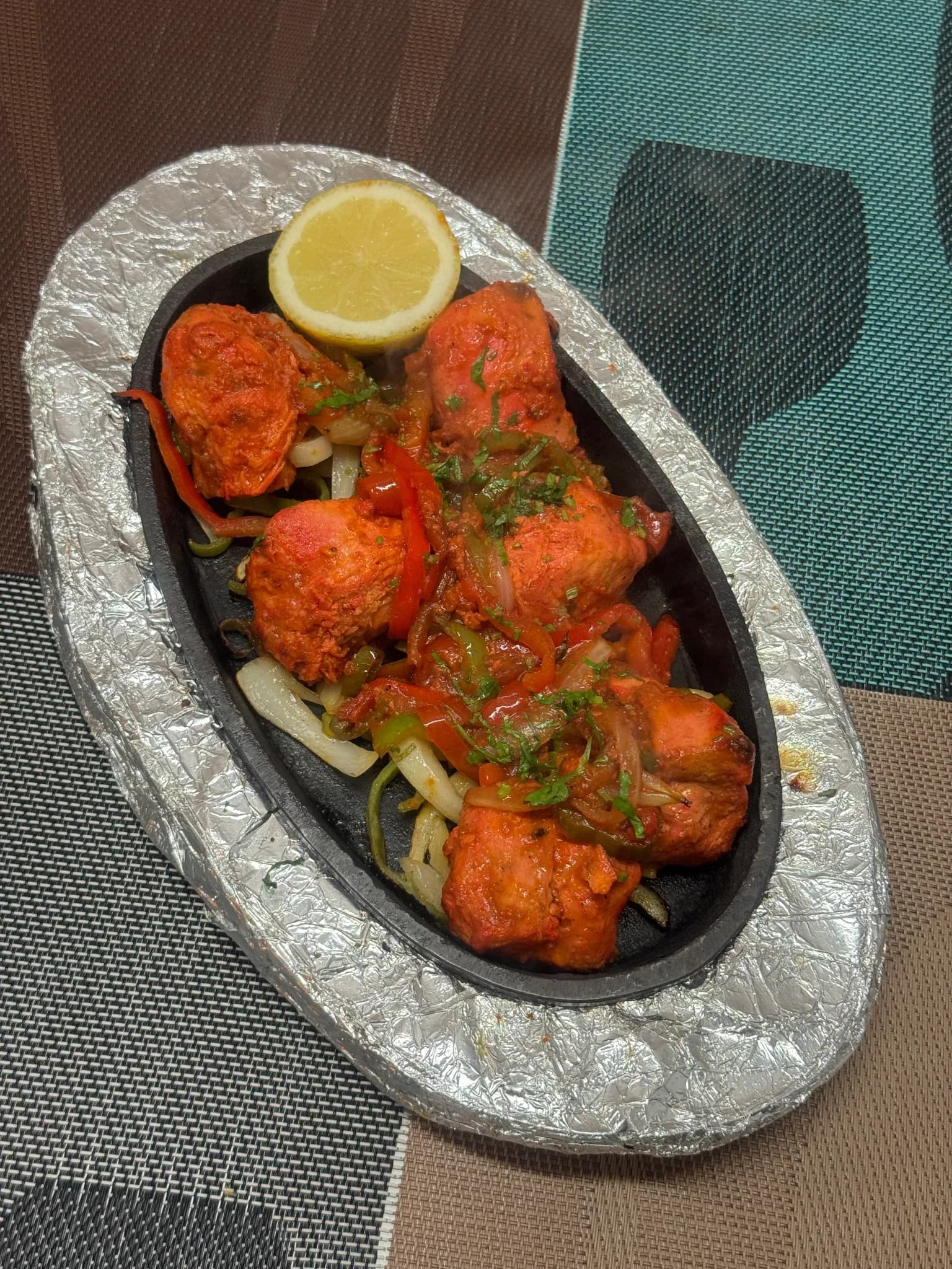 Tandoori Chicken Tikka servido sobre cebolla y pimiento salteados con rodaja de limón en Royal king indian cuisine, Barcelona